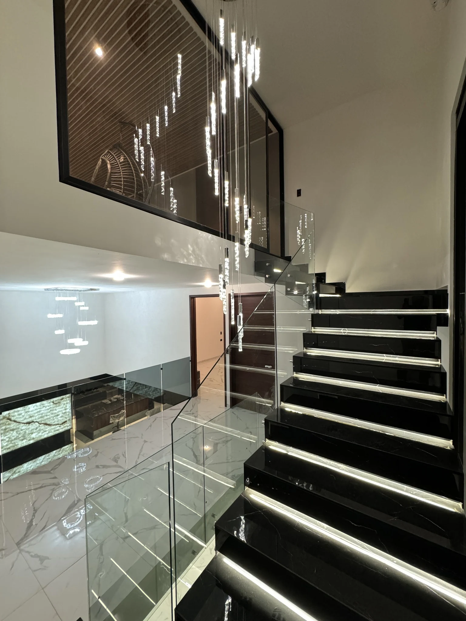 Escalera negra con iluminación LED y barandal de cristal